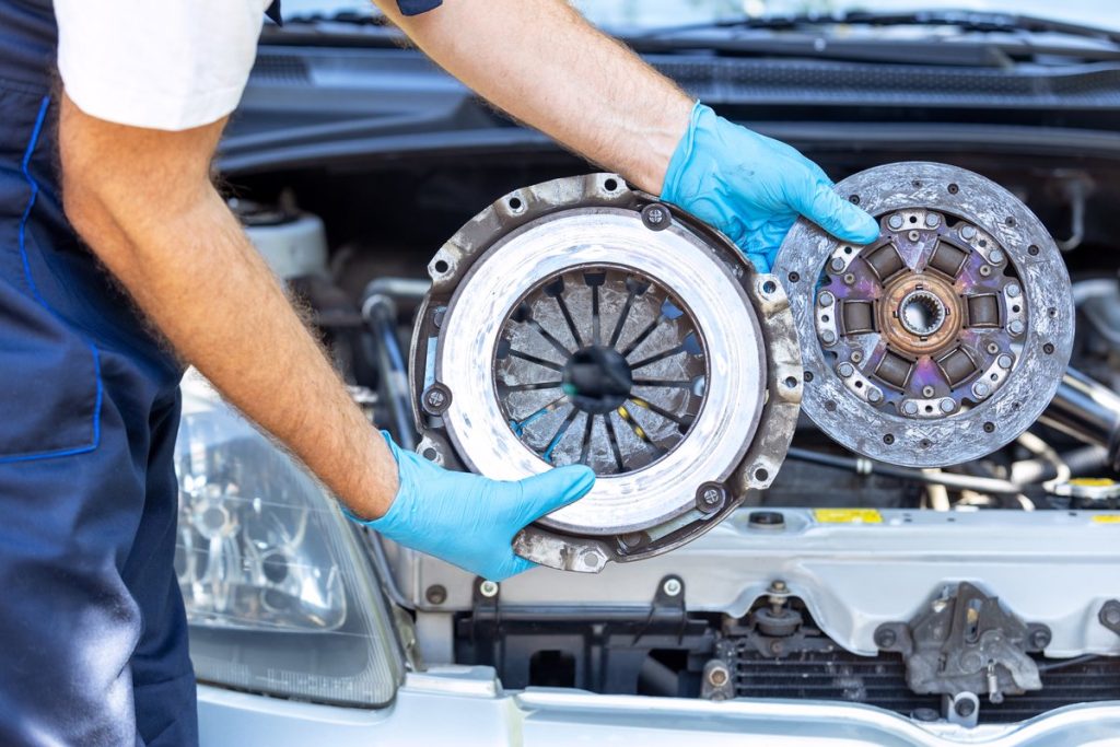 Technician holding a clutch disc and pressure plate during a clutch service