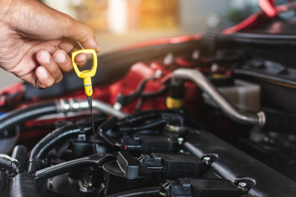 Hand pulling the engine oil dipstick to check the oil level