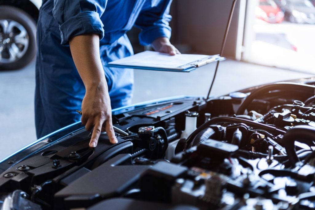 Technician carrying out a maintenance inspection under the hood of a car